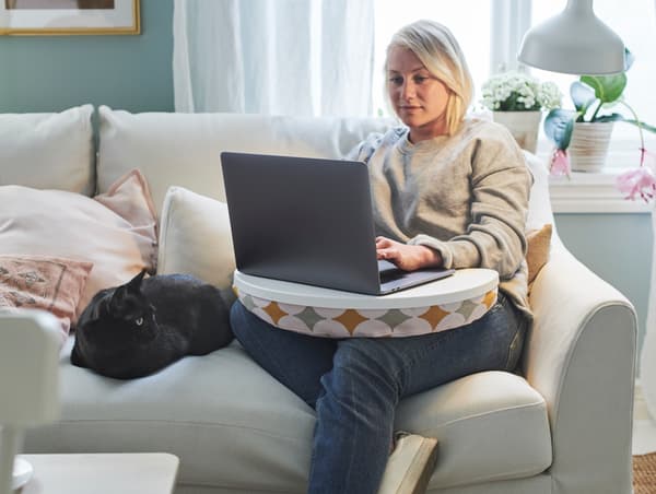 A woman working from home using BYLLAN laptop support.