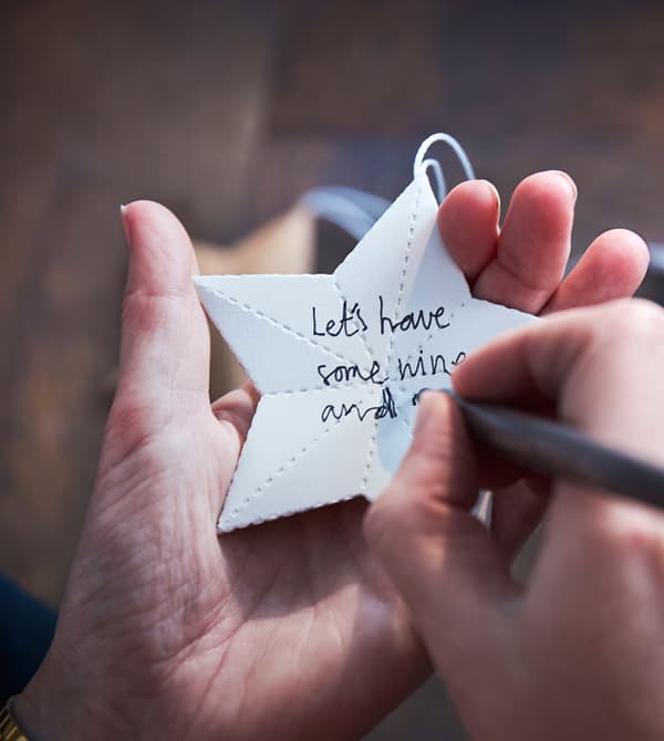 A woman writes a holiday wish on a paper star.
