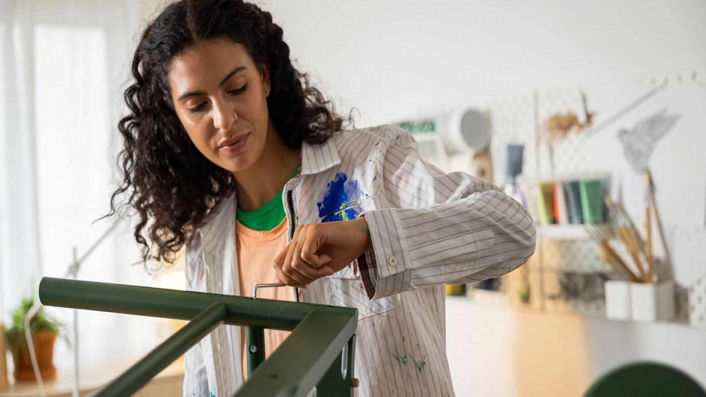 A women is fixing the screw of a green chair