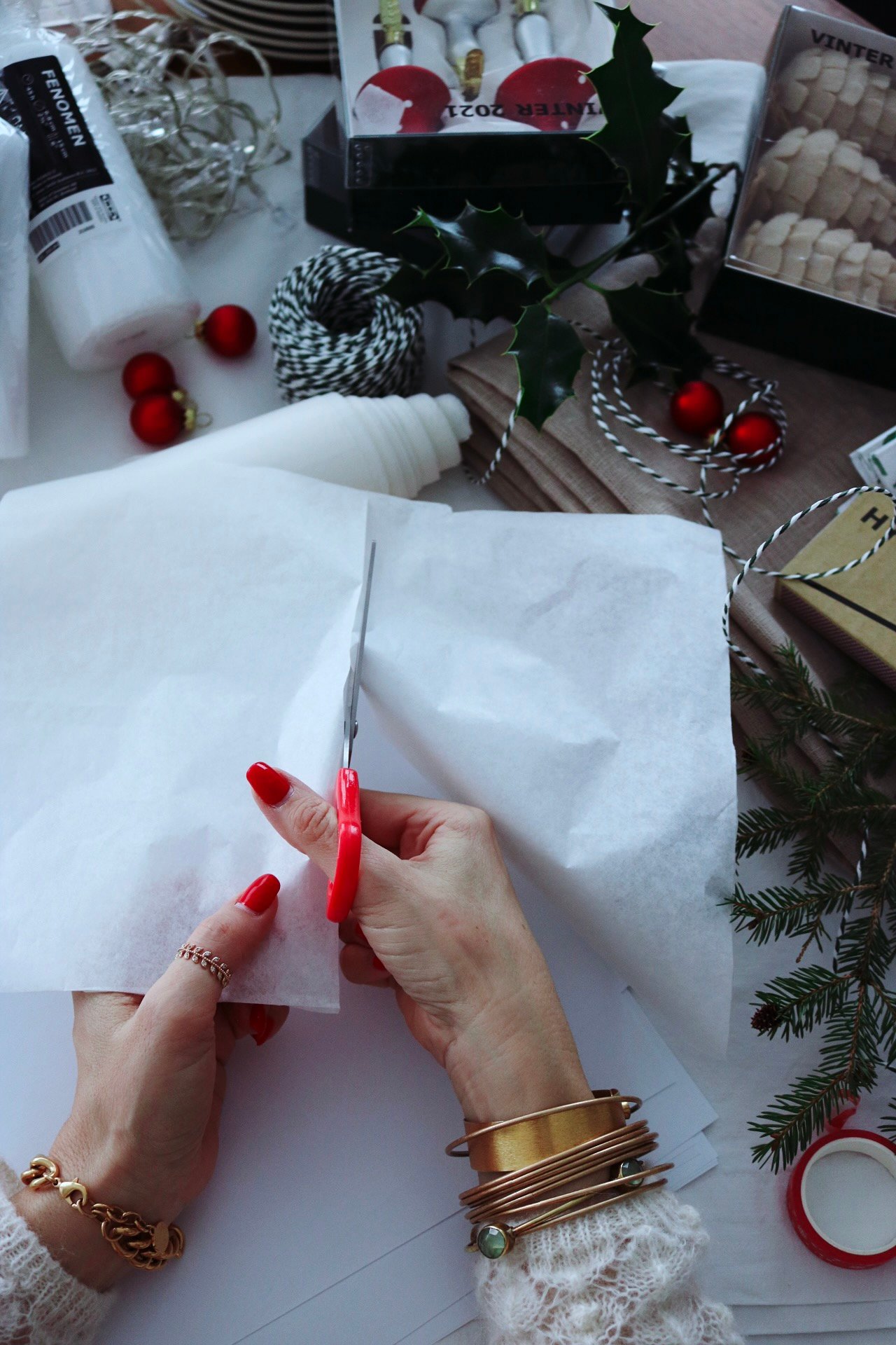 A womens hands cutting a white tissue paper with scissors