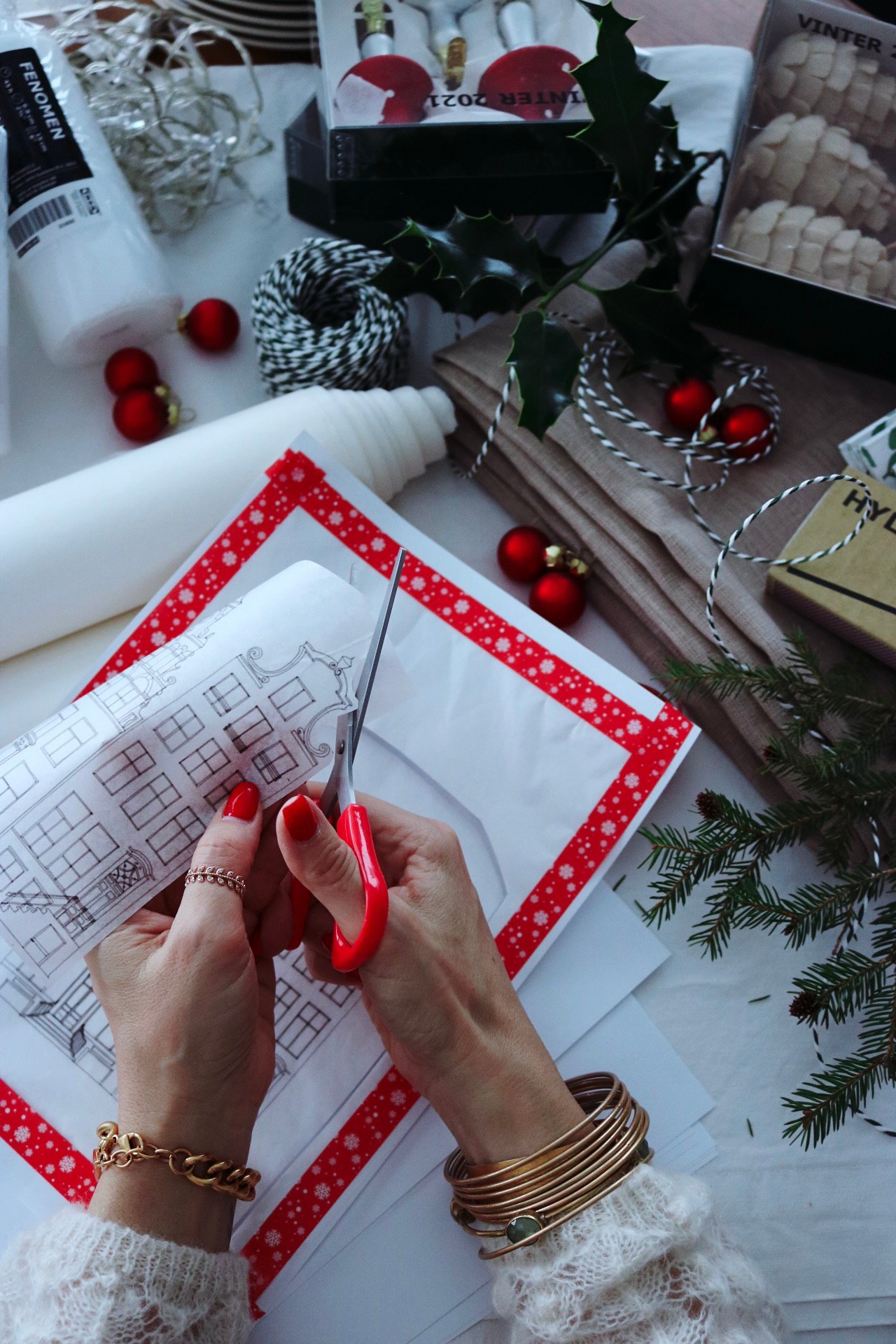 A womens hands cutting out the design with red scissors