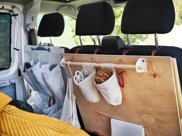 A wooden board hooked to the front seats and two hanging containers hanging from the rail