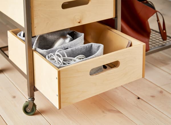 A wooden box being used for workspace storage in a movable bench.
