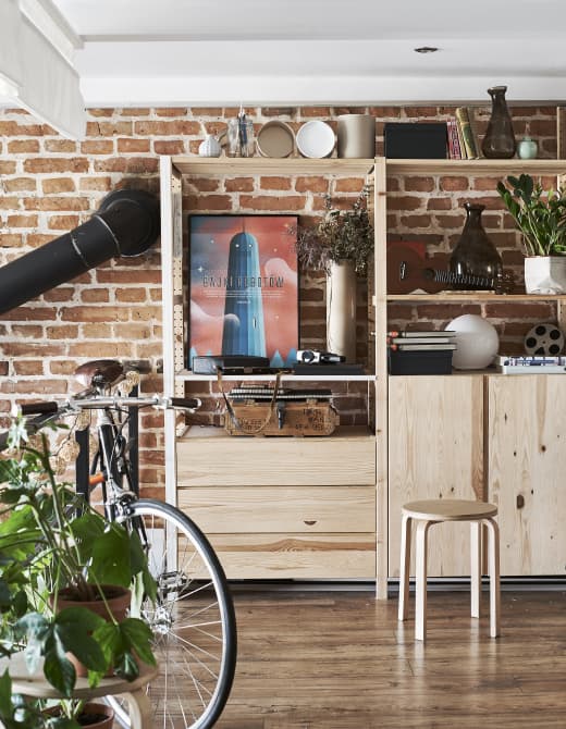 A wooden cabinet and shelves against a brick wall.
