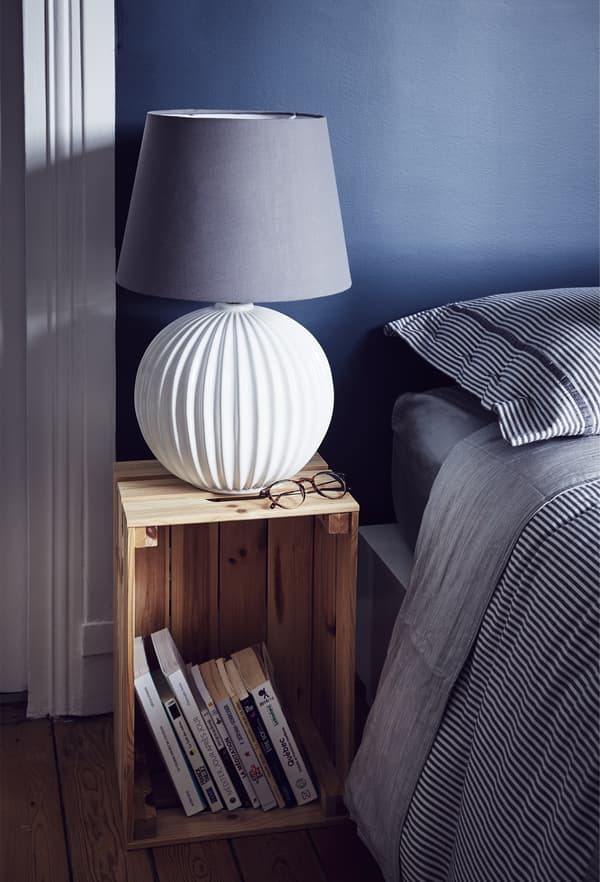 A wooden crate turned on its side to become a bedside table now holds a white lamp.