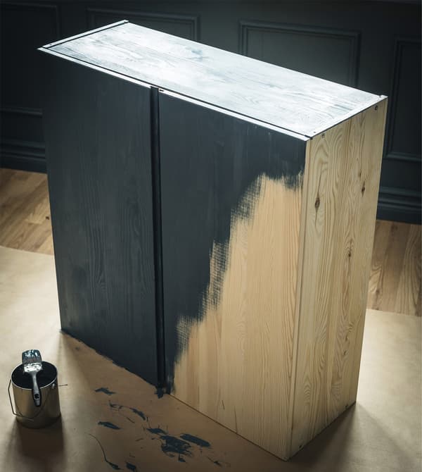 A wooden IVAR cabinet is being customised with green paint.