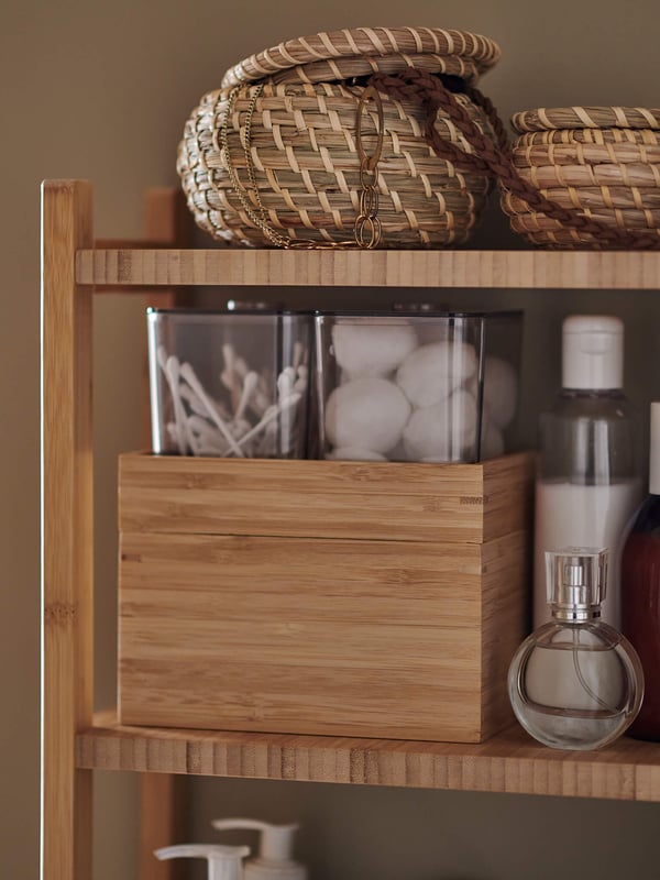 A wooden shelf with organizers, baskets, and bathroom accessories sitting on it.