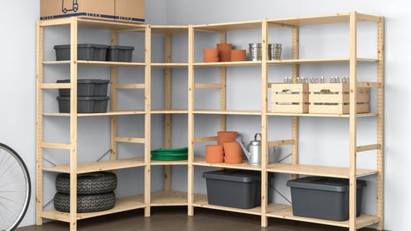 A wooden shelving unit is filled with various storage boxes, flower pots, tires, and other items.
