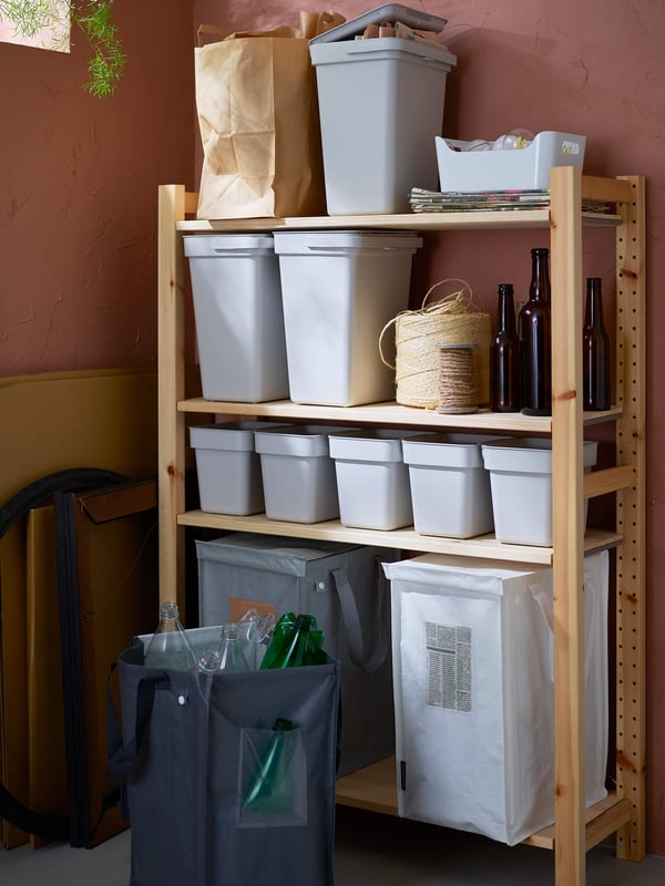 A wooden shelving unit with several light colored bins in the corner of a room.