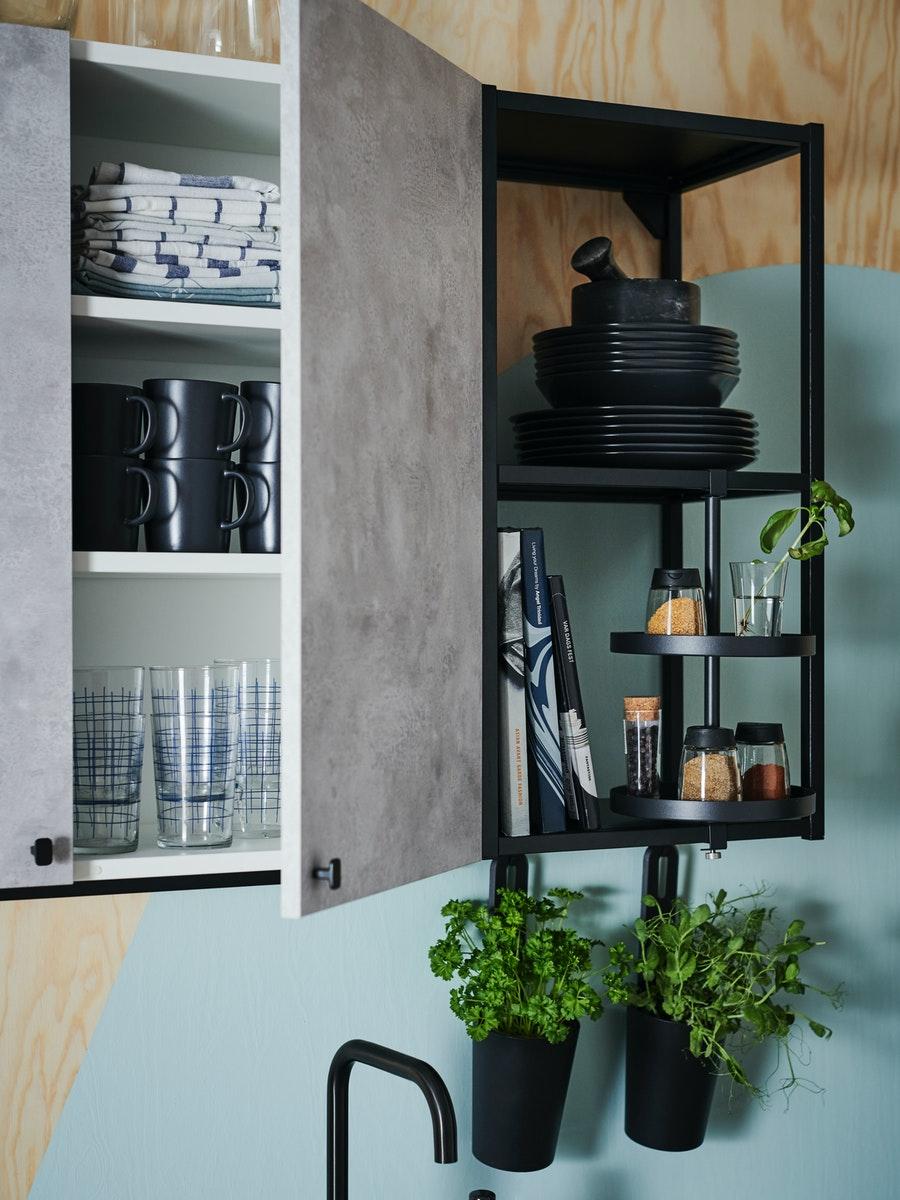 A wooden wall with green paint and an ENHET wall cabinet with assorted tableware.