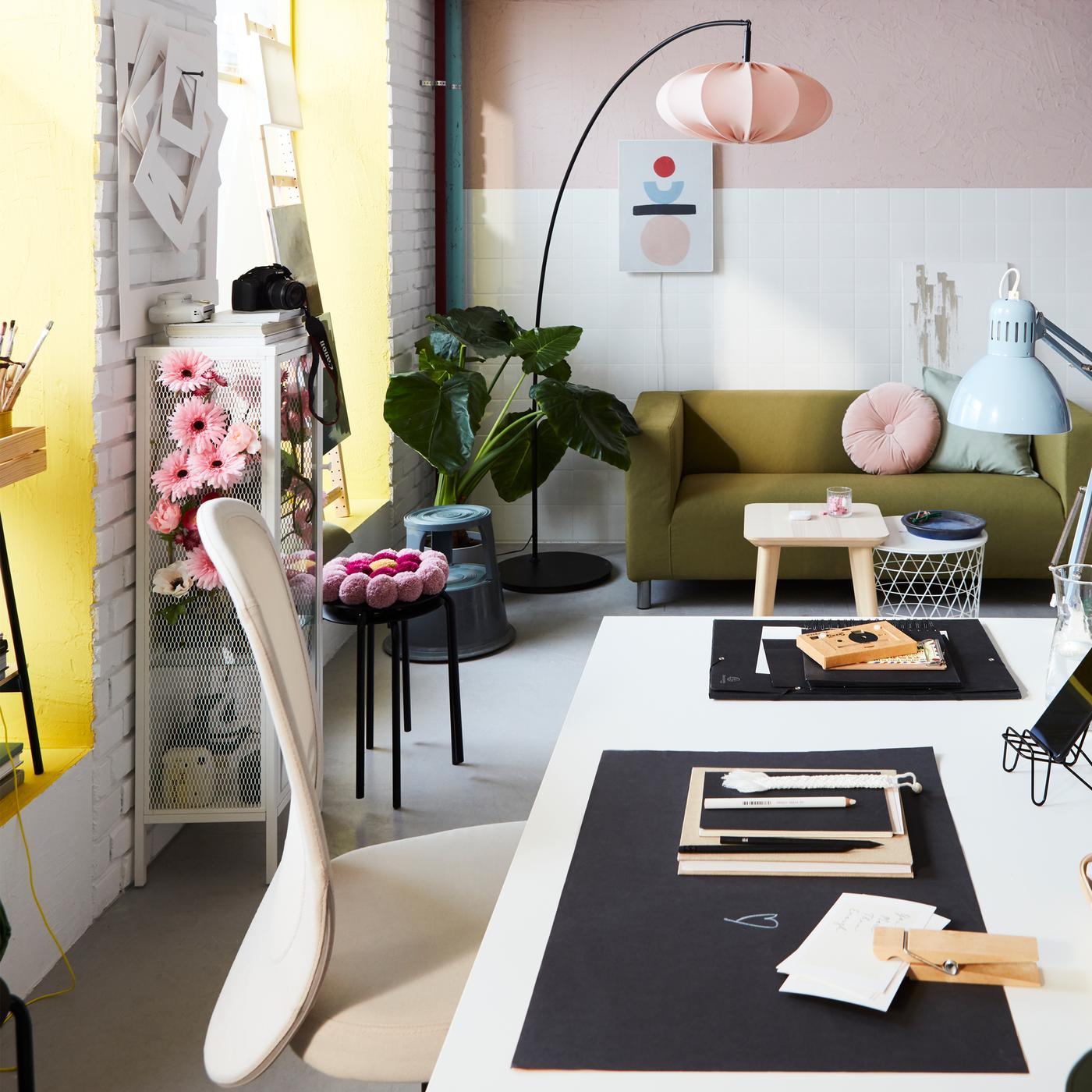 A workspace with a TROTTEN desk, a FLINTAN office chair and pink accents. At the back is a tall, curved floor lamp.