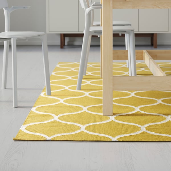 A yellow and white IKEA rug displayed in a dining room