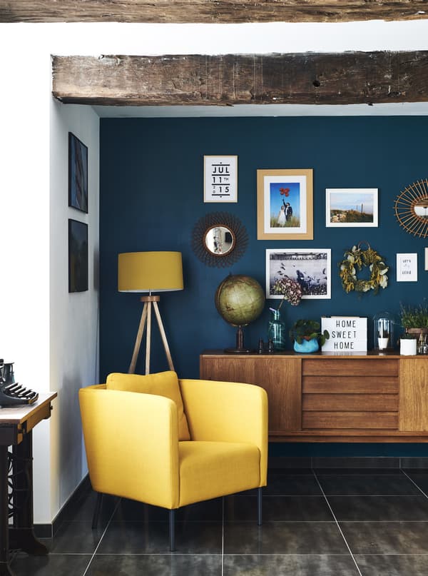A yellow armchair against a dark blue wall.
