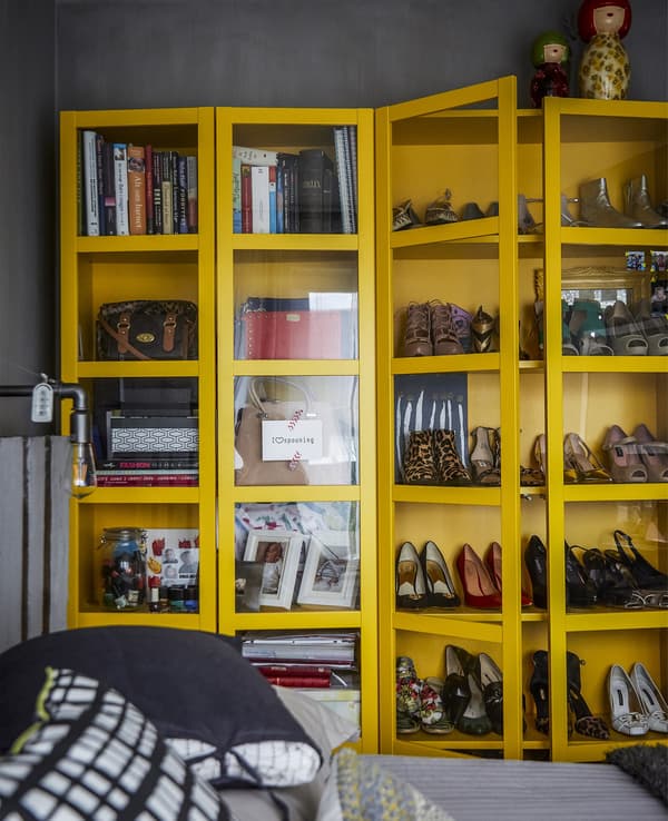 A yellow cabinet displaying shoes and books.