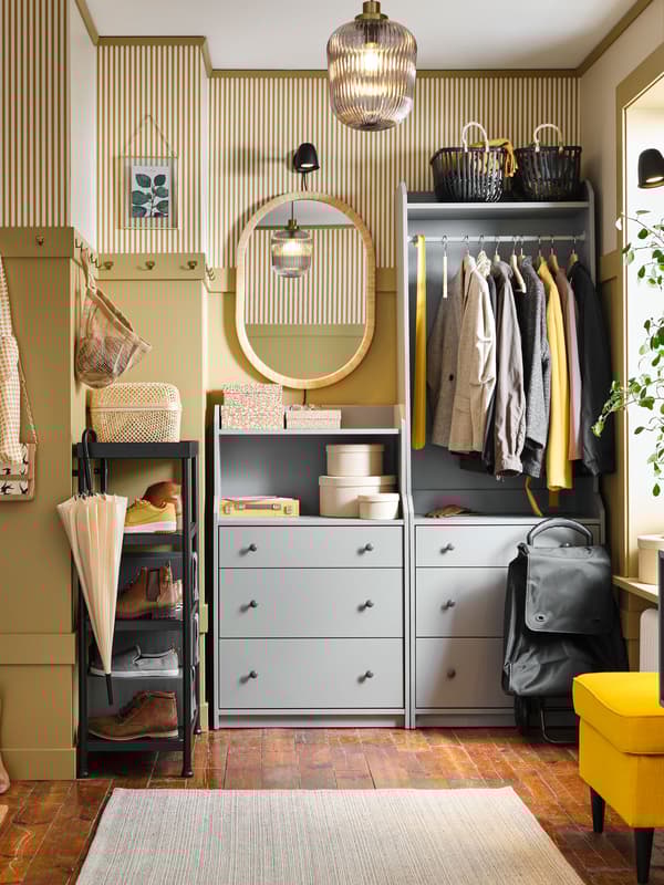 A yellow hallway with a grey HAUGA open wardrobe and chest of drawers in it. Coats are on the rail and a mirror is beside it.