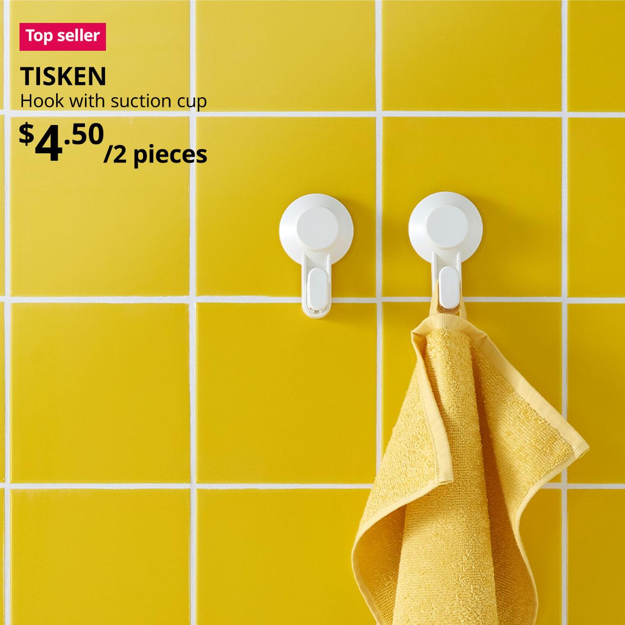 A yellow hand towel is hung on a white TISKEN hook with suction cup is placed on yellow squared tiles in a bathroom setting. Text on image reads "TISKEN, Hook with suction cup. Price at $4.50/2 pieces."