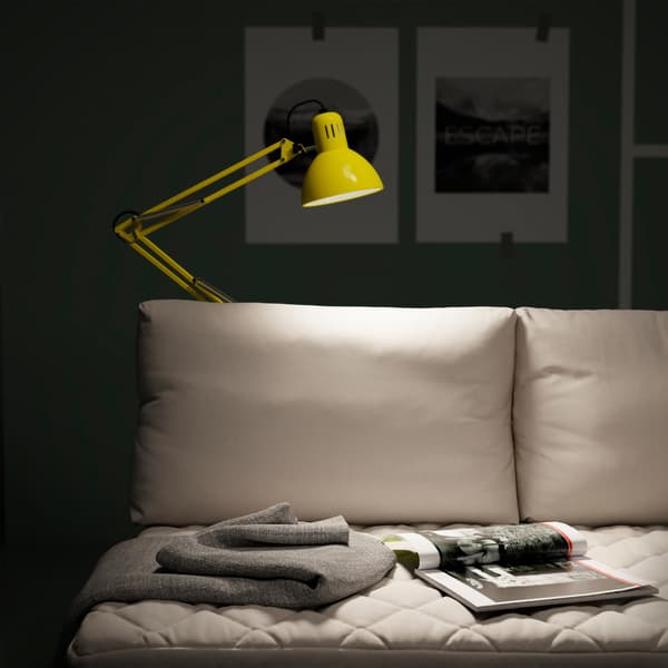 A yellow IKEA TERTIAL portable work lamp comes with an adjustable head and arm. Here it illuminates a reading zone on a sofa.