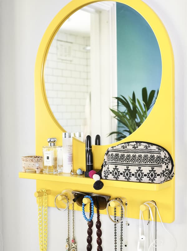 A yellow mirror with built-in pegs and shelf.
