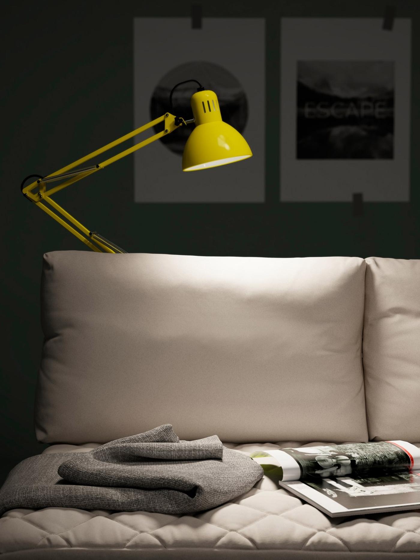 A yellow TERTIAL portable work lamp comes with an adjustable head and arm. Here it illuminates a reading zone on a sofa.