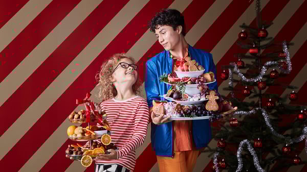 A young adult and child holding platters of food. 
