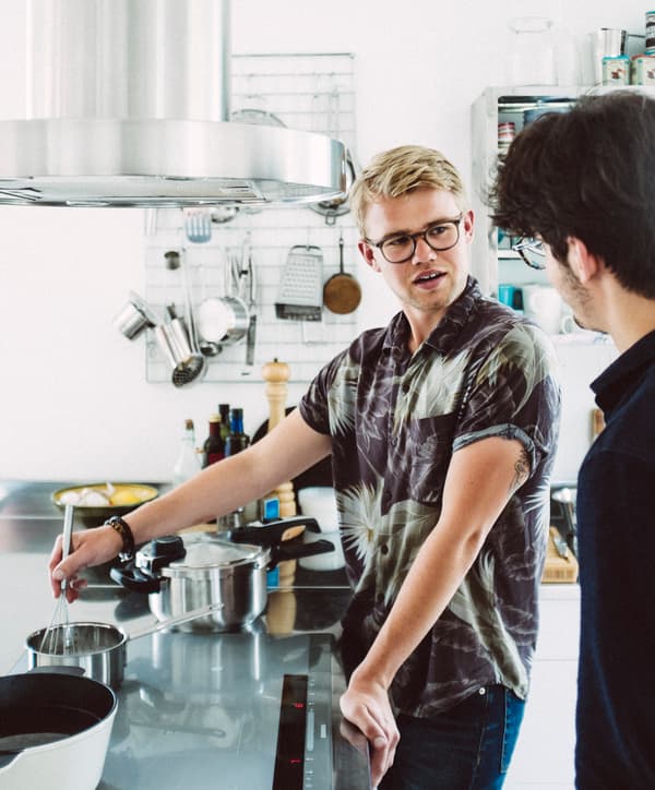 A young man stirring a pot on a stove in a modern kitchen.