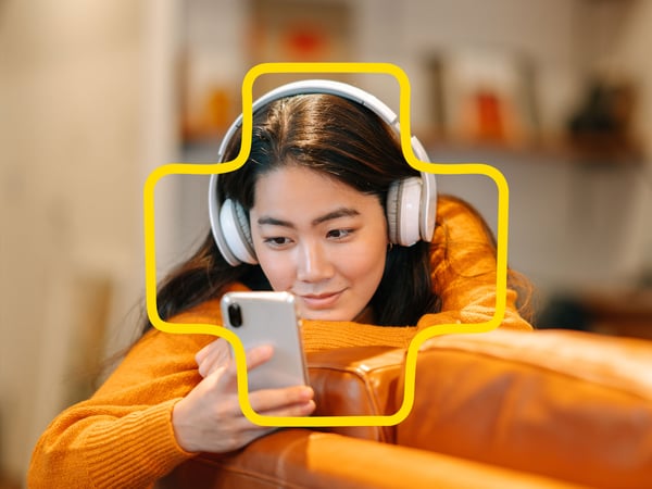 A young person leans on the sofa and scrolls through her phone.