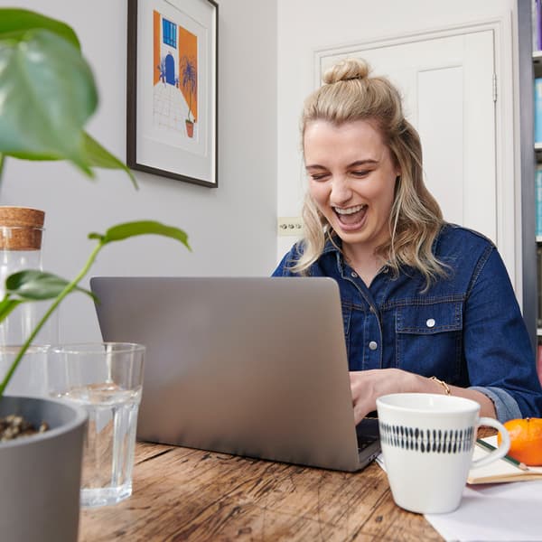 A young woman smiling in front of her laptop