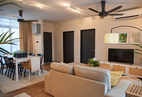 A zoomed-out room setting featuring a sofa, chest of drawer and dining area.