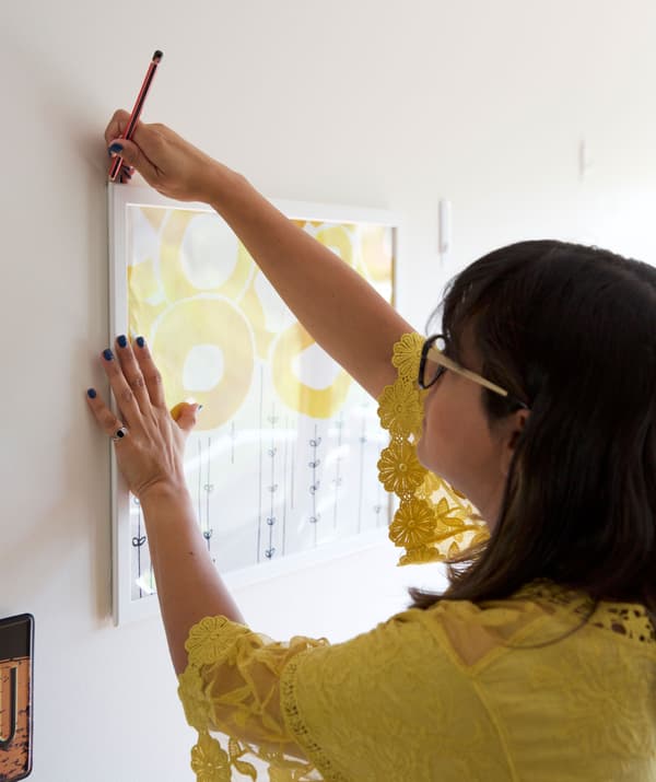 Abeer en train de marquer les coins d’un cadre sur un mur blanc.