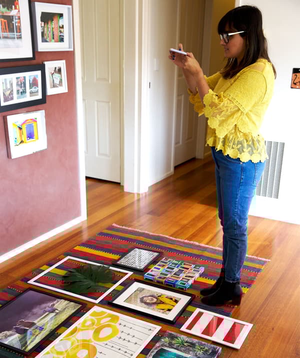 Abeer facendo unha foto de varias imaxes enmarcadas sobre unha alfombra.