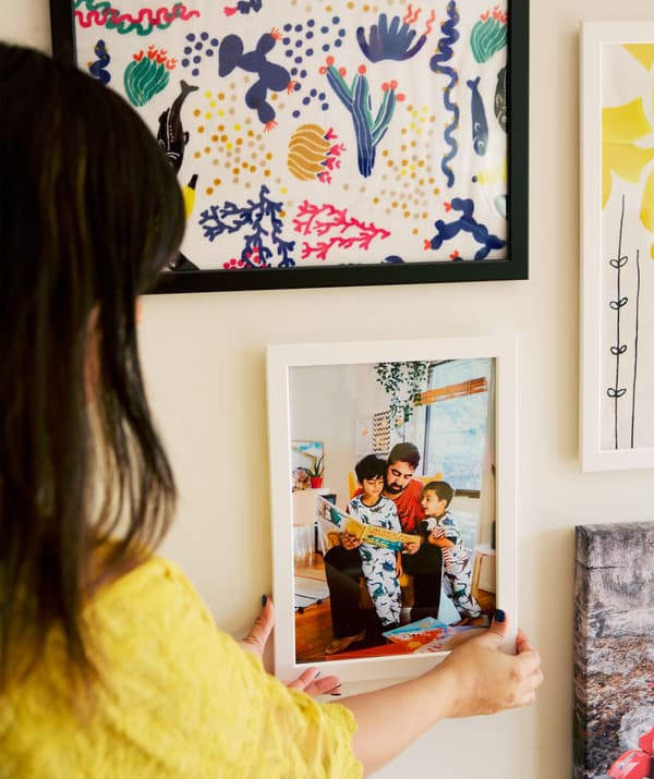 Abeer henger opp et familiebilde på en gallerivegg med bilder.