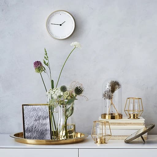 Accesorios de decoración metálicos e un arranxo floral sobre un moble branco