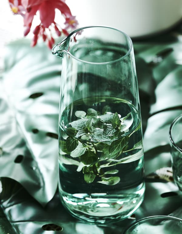 Acqua e menta in una caraffa verde su foglie artificiali - IKEA