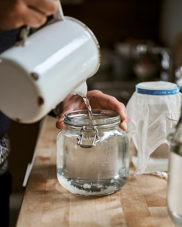 Acqua versata da una brocca smaltata bianca in un contenitore in vetro in stile Kilner - IKEA