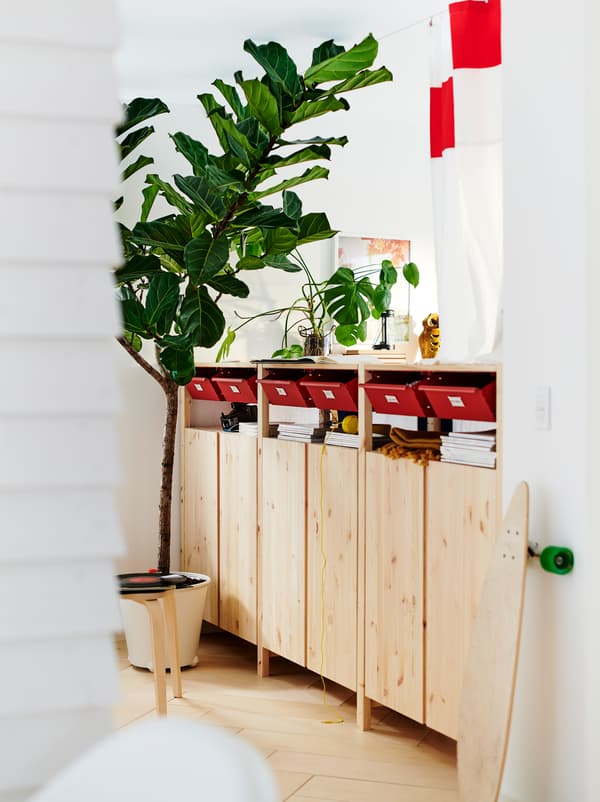 Across the floor of a white room is a row of IVAR cabinets, doubling as room divider, with a mix of open and closed storage.