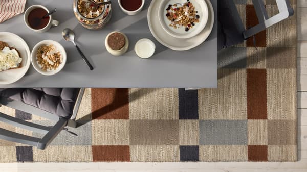 Aerial view of an earth tone colored rug with a table set with breakfast items