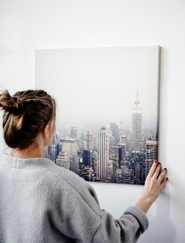 Agnes en train d’accrocher une reproduction représentant un paysage urbain