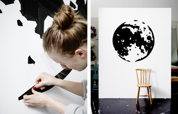 Agnes en train d’appliquer de l’adhésif au mur. Mur avec représentation de la Terre en adhésif