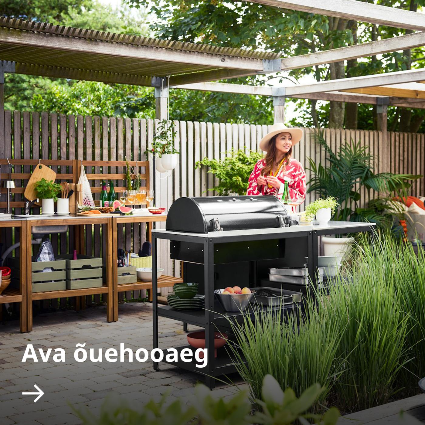 Aiavaade musta GRILLSKÄR söegrilli ja puidust NÄMMARÖ õueköögi moodulitega, mis asuvad pergolas lahtise katuse all.