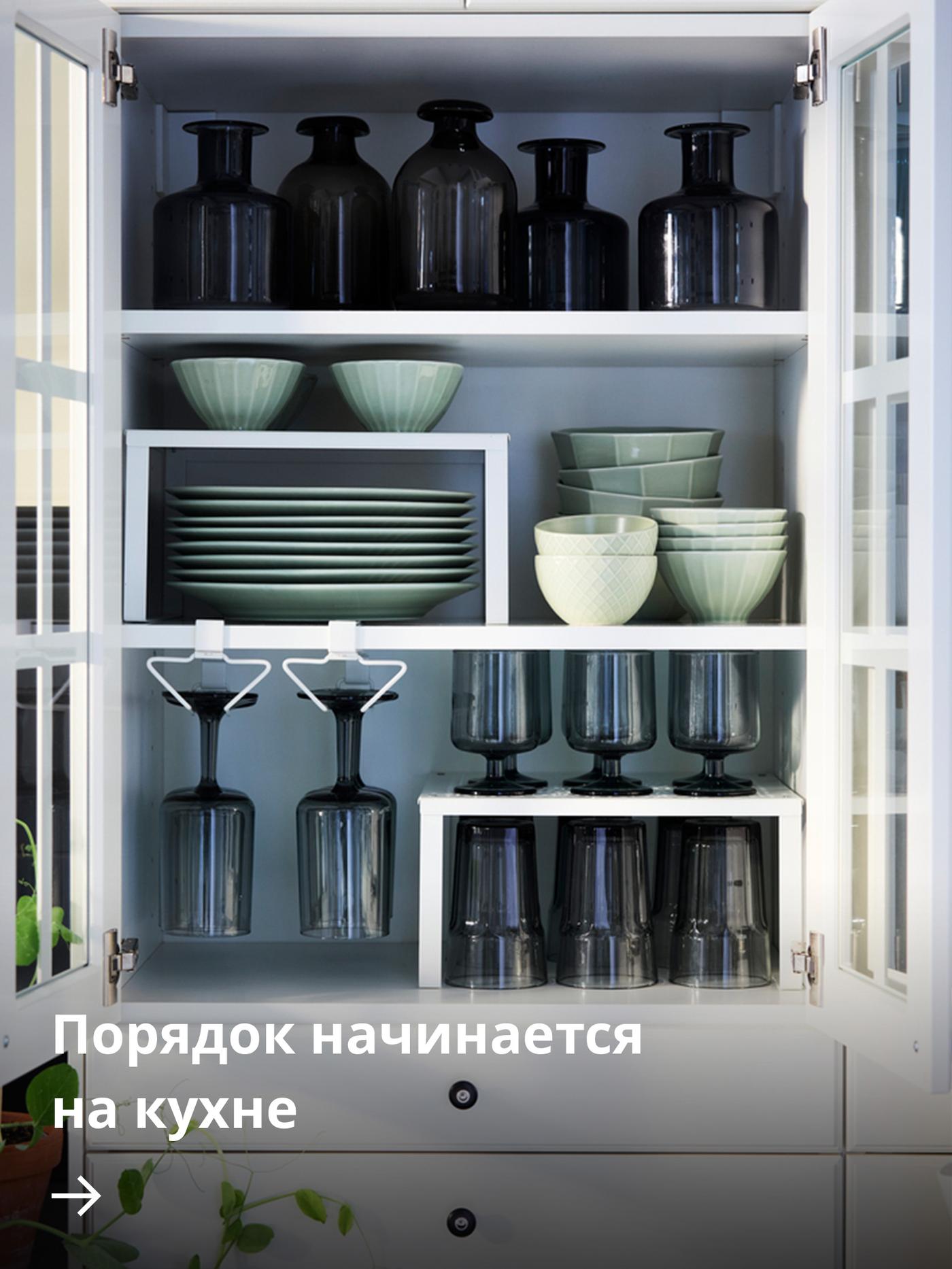 Аккуратно организованный настенный кухонный шкаф с органайзерами PÅLYCKE, в которых расставлены посуда и стаканы.