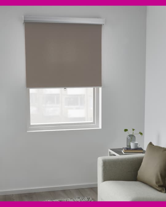Al costado de un sofá en una sala de estar hay una ventana con una cortina roller de IKEA.
