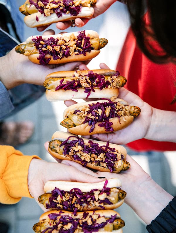 Alcune persone tengono in mano degli hot dog vegetariani.