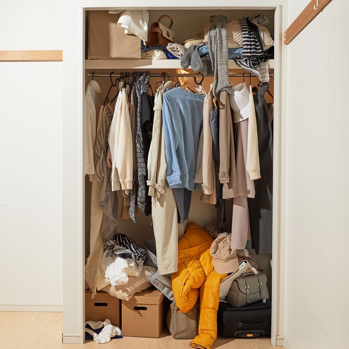 Alcuni abiti sono riposti in disordine all'interno di una cabina armadio tramite appendini o cassetti. Nell'armadio ci sono anche delle scatole di cartone, borse e valigie colorate.