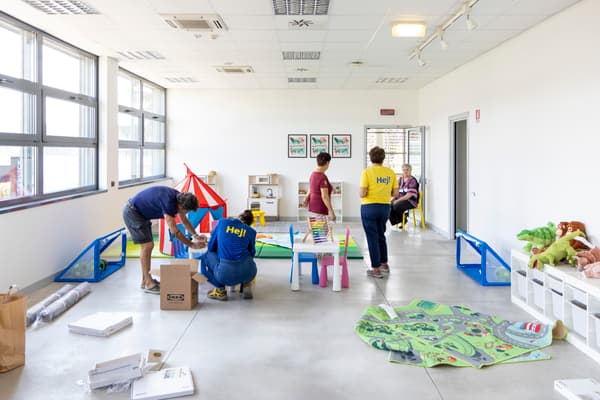 Alcuni co-worker mentre stanno montando e allestendo diversi mobili, accessori e giochi in una struttura destinata ad ospitare donne e bambini ucraini.