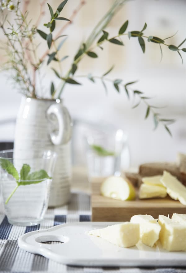 Aliments tranchés présentés sur des planches à découper, un verre d’eau et un centre de table tout simple