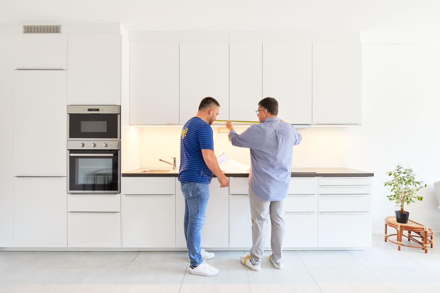 All’interno di una cucina IKEA bianca in un appartamento di nuova costruzione, un collaboratore IKEA parla con il proprietario del complesso edilizio. 