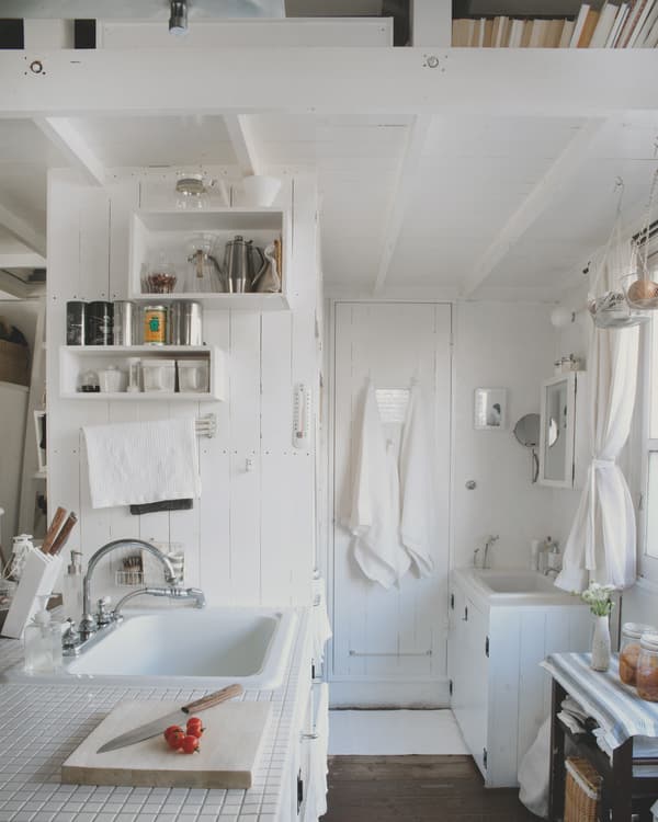Almacenaje de cocina y una organizada zona de lavabo en una casita blanca de Tokyo.