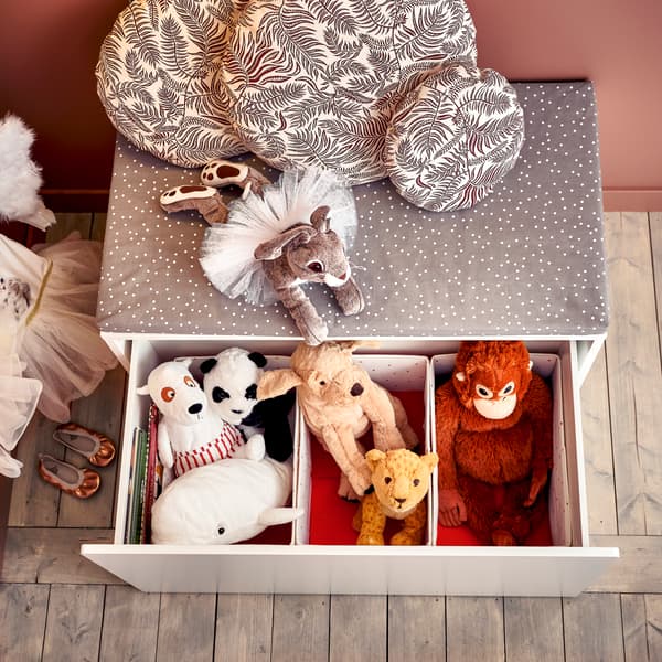 Almacenaje gris con cajones con peluches de oso, perro, mono y más en su interior.