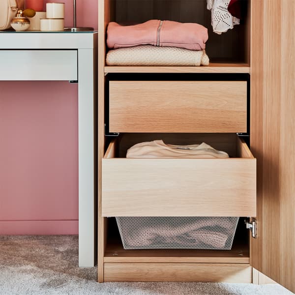 Almari pakaian berlaci dalam kesan kayu oak berwarna putih, meja solek berwarna putih, dinding berwarna merah jambu dan ambal berwarna kelabu.