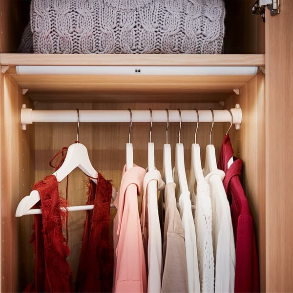 Almari pakaian dalam kesan kayu oak berwarna putih yang mempunyai lampu, rel pakaian dan penyangkut berwarna putih.